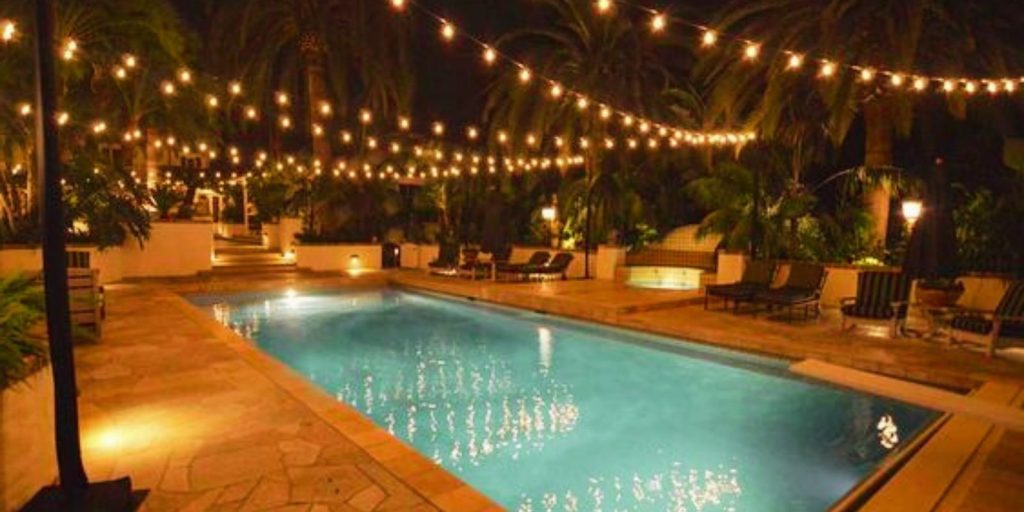 A pool surrounded by chairs, set in a leisure center or resort area at night. 