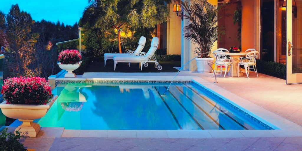 A Plunge Pool with a Lounge Chair and a table surrounded by chairs. 