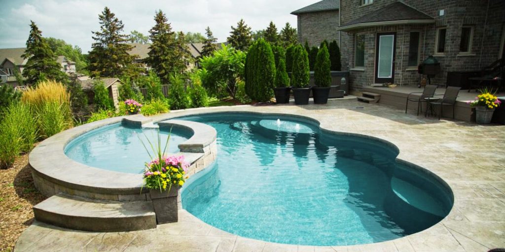 The pool is surrounded by plants and trees, with a clear blue sky in the background.