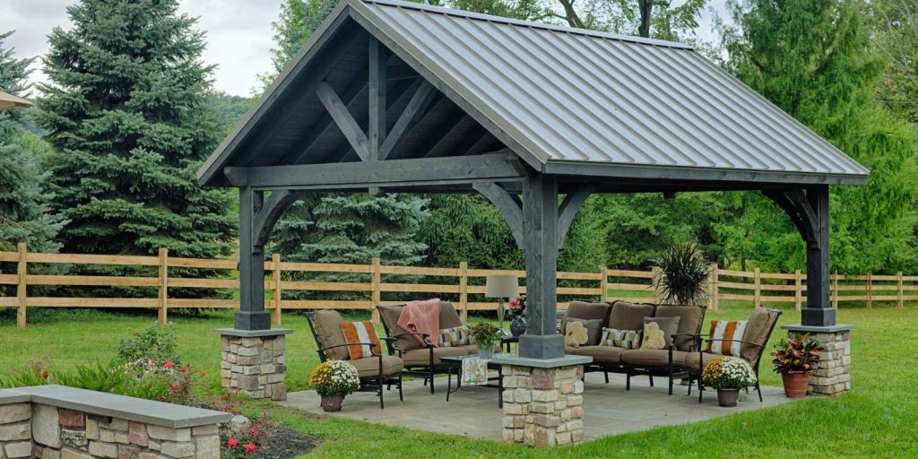 The outdoor setting includes plants, trees, grass, a bench, and a wooden pavilion gazebo