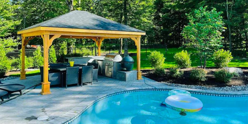 Pool with a gazebo and chairs around it in an outdoor setting. 