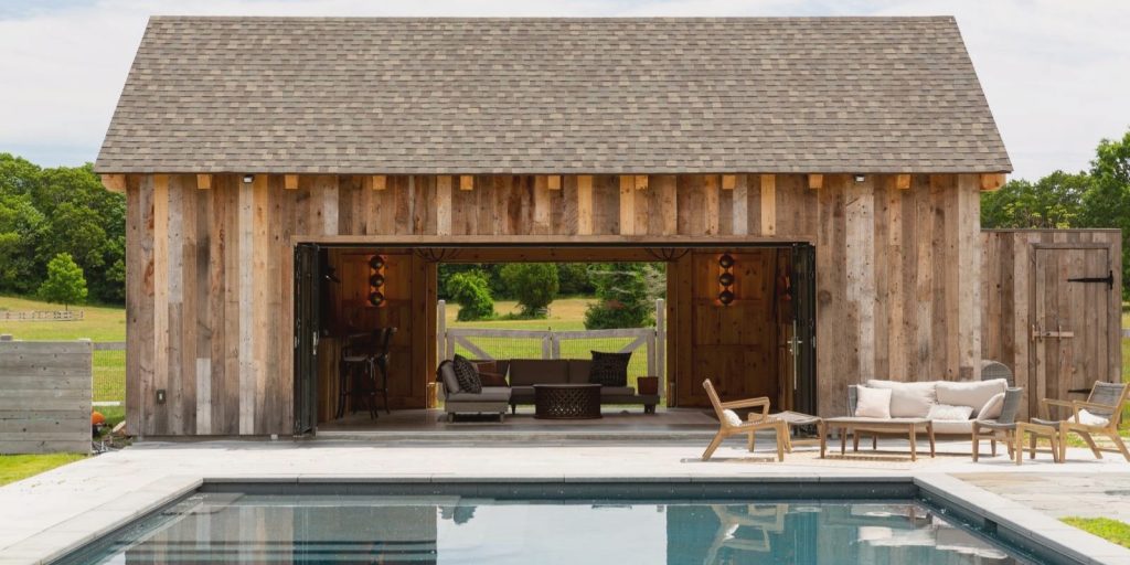  A classic house shed with a pool, surrounded by trees and outdoor furniture.