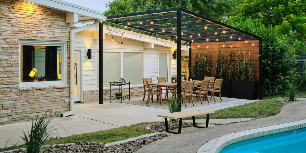 A pergola with built-in lighting featuring a table and chairs, set in an outdoor space. 