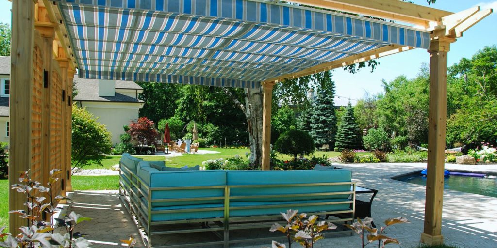 A covered pool with a shaded area including benches, chairs, and a pergola.