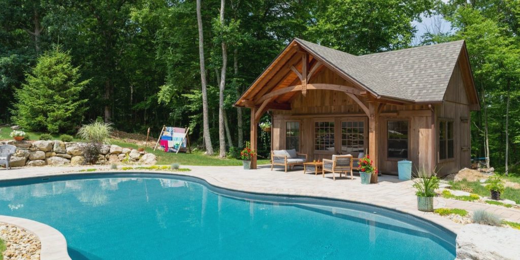 A swimming pool shed located in front of rustic farmhouse 