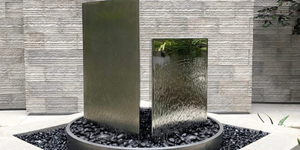  A modern fountain placed outside a building.