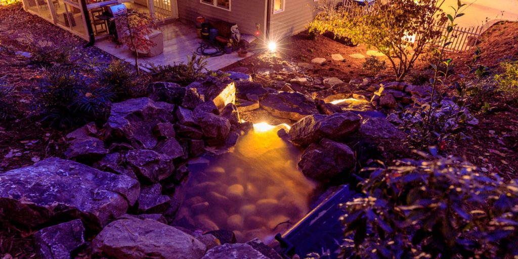  A Naturalistic stream pond with a fire pit surrounded 