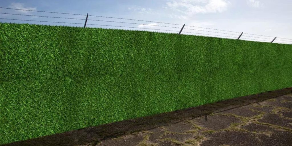  Artificial outdoor grass wall under a clear sky with a fence in the background