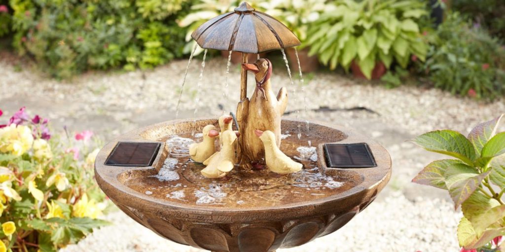  A fountain with solar plate and umbrella placed nearby.