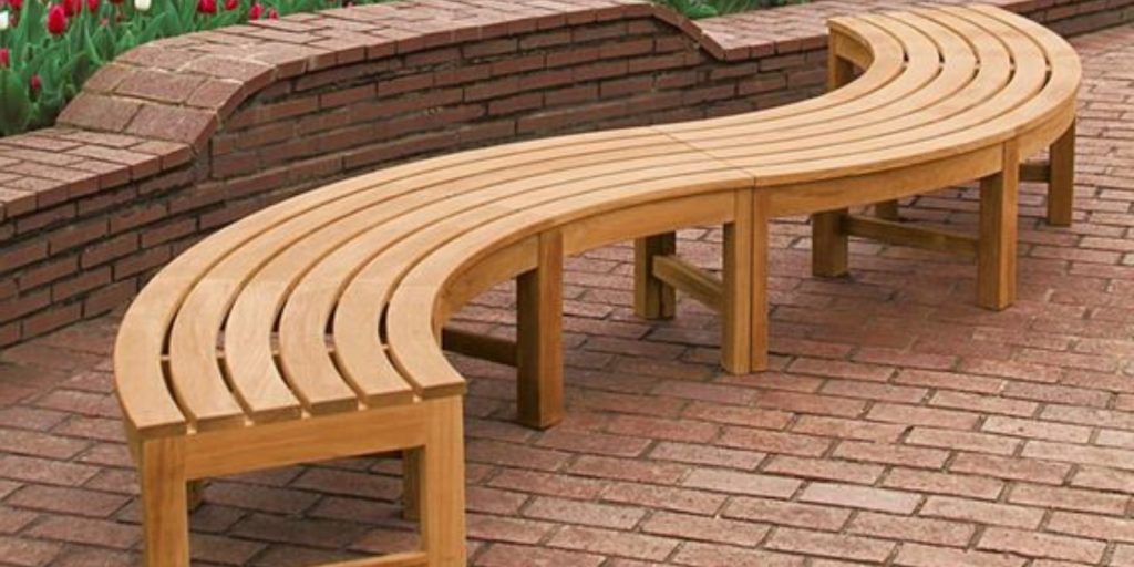 A backless wooden bench placed on a brick surface