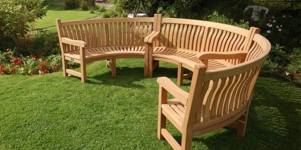 A curved wooden bench situated on a lush green lawn